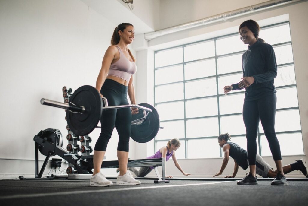 Trainer supervising a gym member performing deadlifts during a strength training session