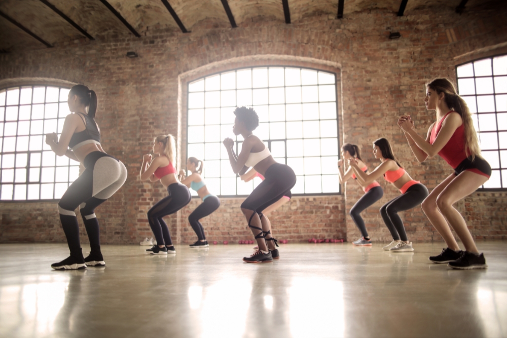 Women doing squats in brick-walled fitness studio