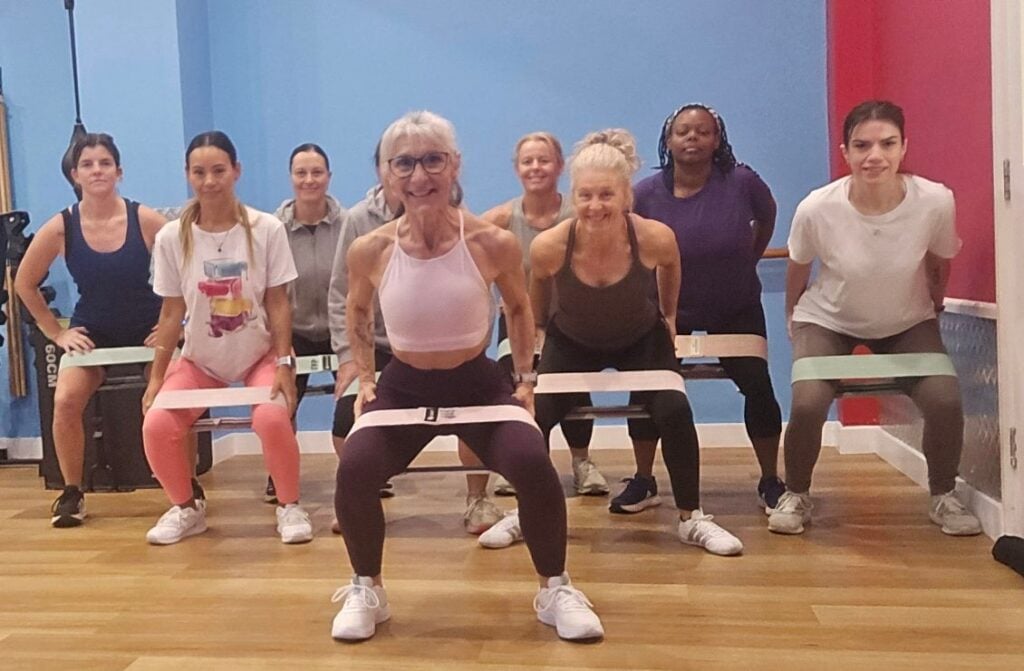 Women doing resistance band squats in fitness studio