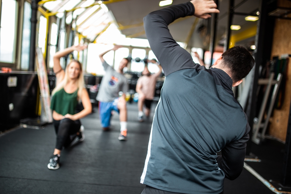 A fitness instructor guiding a group of participants through side-bend stretches during a group workout class.