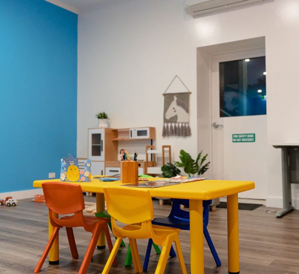 A yellow rectangular activity table with four colourful chairs