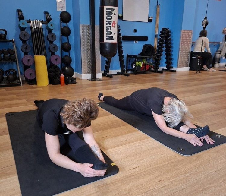Two women holding a seated forward fold during a Stretch-N-Flex class at Active Fitness Medowie